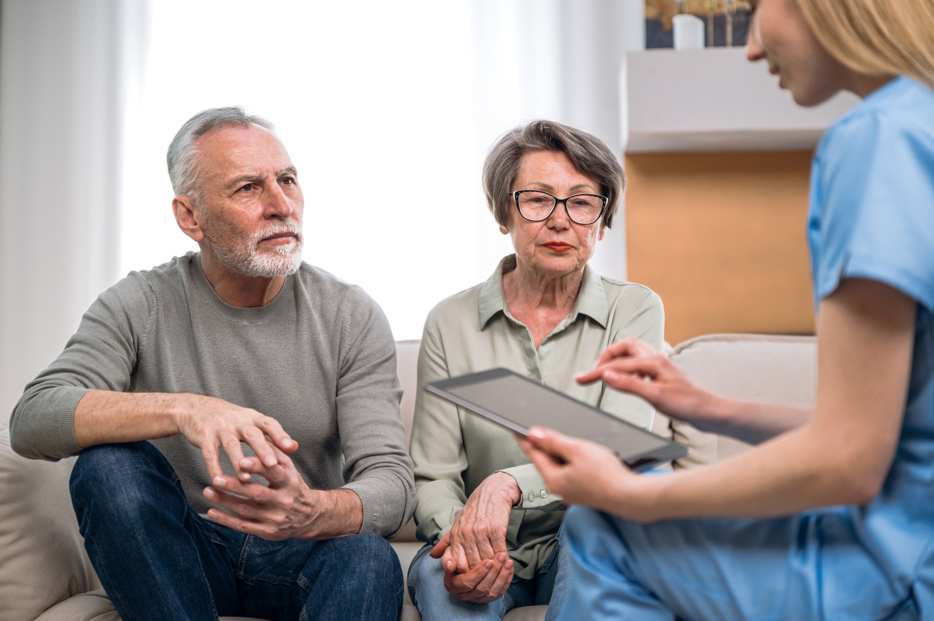 Doctor talk with senior couple, using tablet, making notes to medical cards