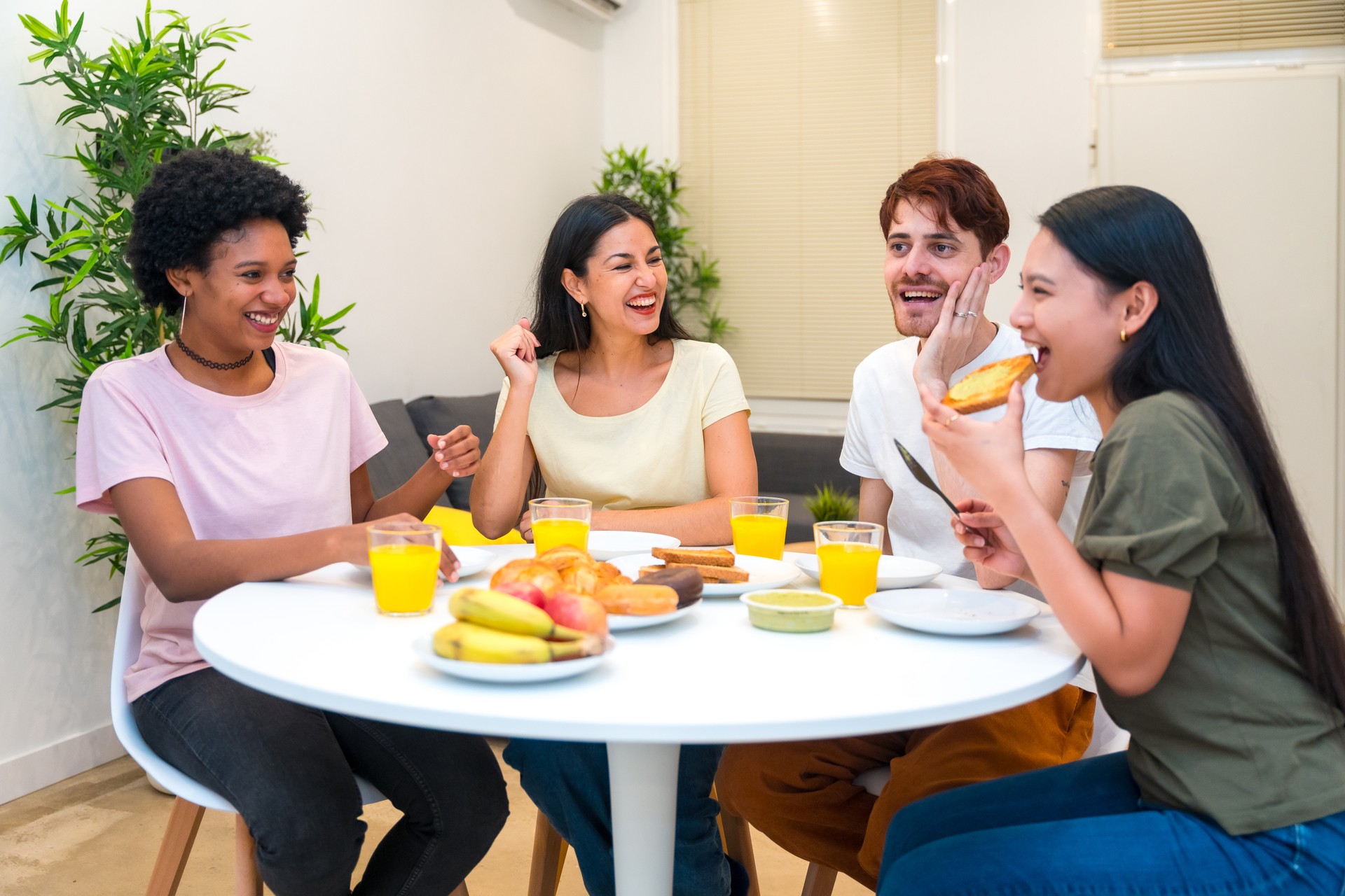 Multi-ethnic friends eating delicious breakfast together at home